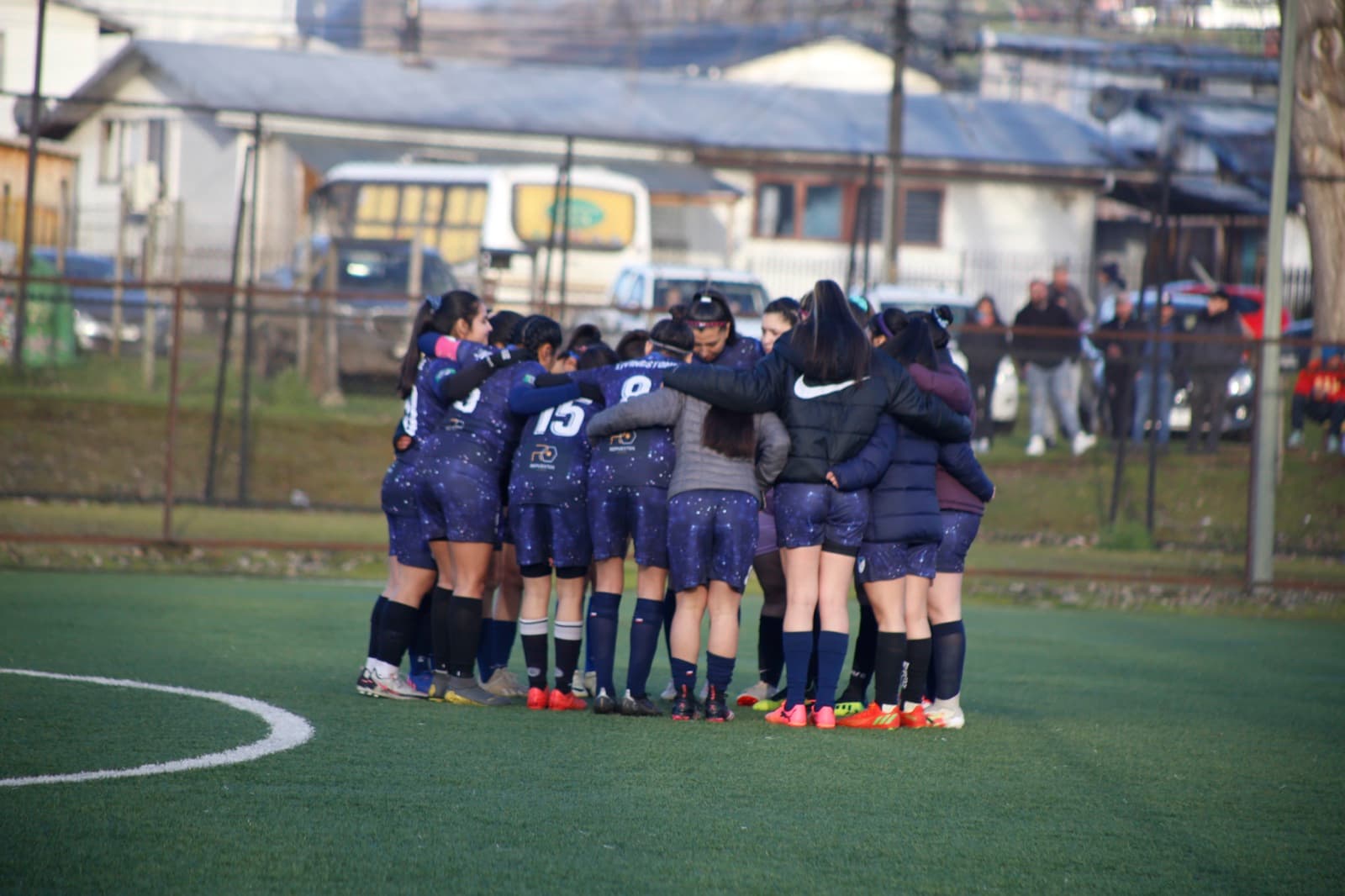 Equipo femenino formado en círculo antes de un partido