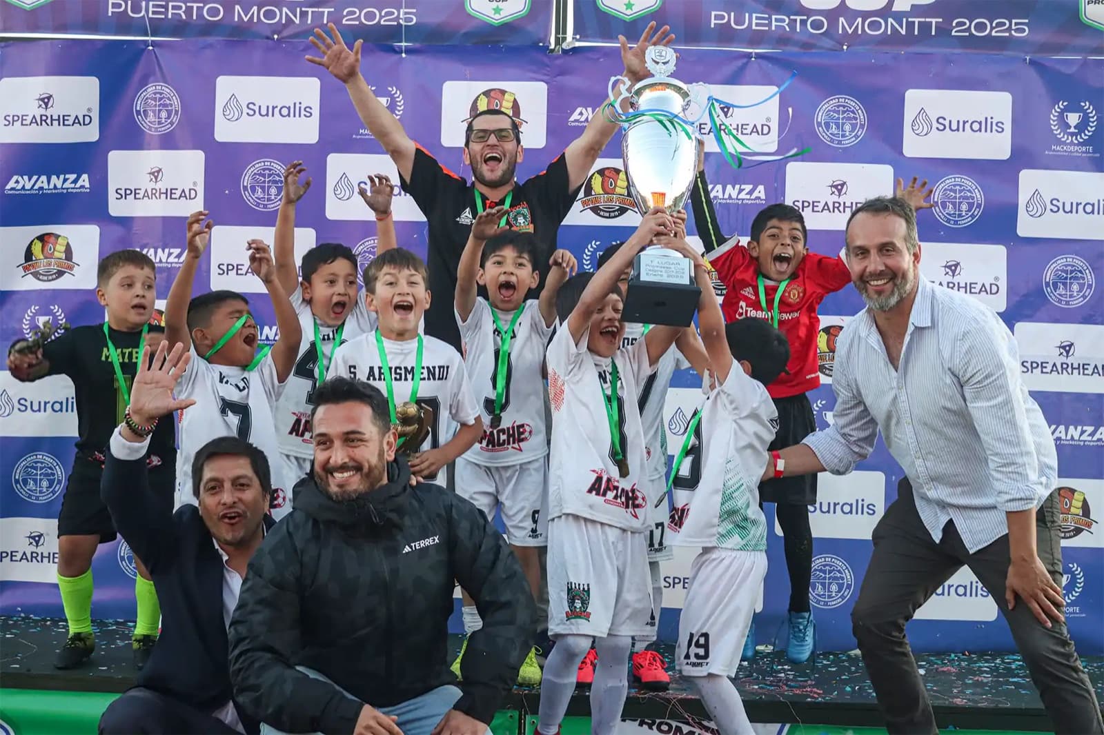 Campeones de Promesas Cup levantando el trofeo frente al muro de auspiciadores