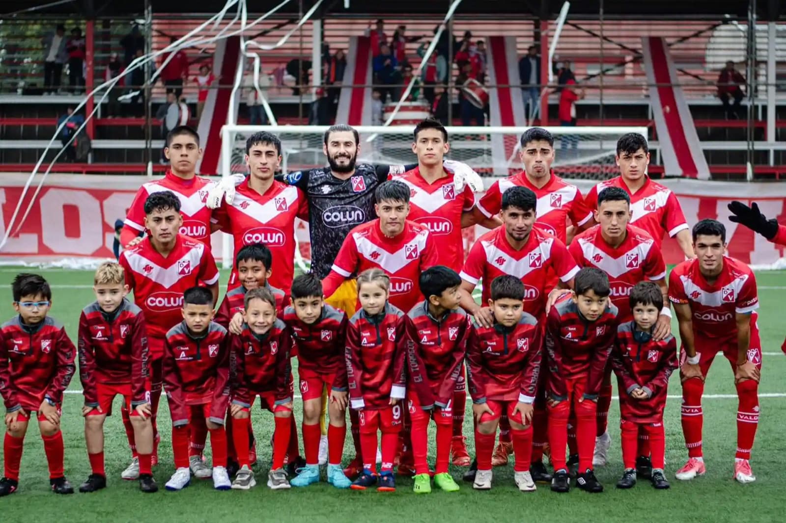 Plantel de Deportes Valdivia posando junto a niños en la cancha